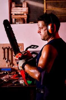 View of a garage mechanic man holding a chainsaw.