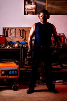 View of a garage mechanic man holding a chainsaw.