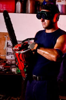 View of a garage mechanic man holding a chainsaw.