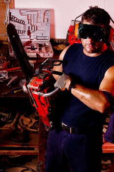 View of a garage mechanic man holding a chainsaw.