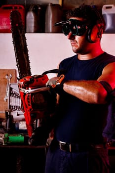 View of a garage mechanic man holding a chainsaw.