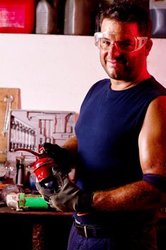 View of a happy garage mechanic man holding a oil can.