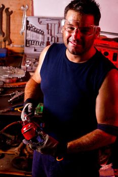 View of a happy garage mechanic man holding a oil can.