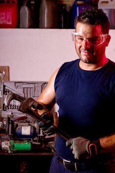 View of a happy garage mechanic man holding an adjustable spanner.