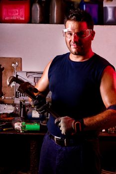 View of a happy garage mechanic man holding an adjustable spanner.