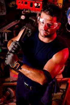 View of a happy garage mechanic man holding an adjustable spanner.