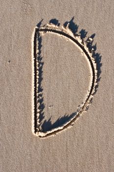 Letter D drawn in the sand. 