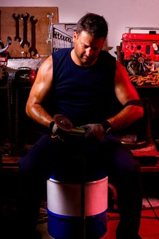 View of a garage mechanic man holding a power saw.
