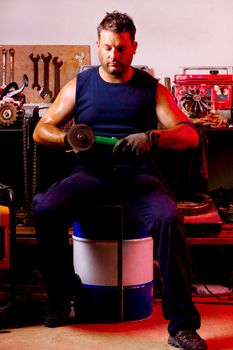 View of a garage mechanic man holding a power saw.