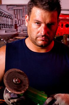 View of a garage mechanic man holding a power saw.