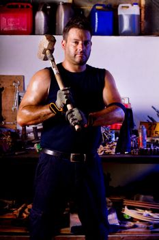 View of a garage mechanic man holding a big hammer.