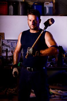 View of a garage mechanic man holding a big hammer.