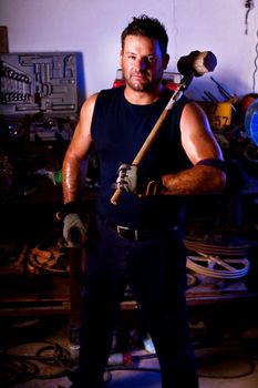 View of a garage mechanic man holding a big hammer.