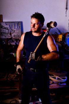 View of a garage mechanic man holding a big hammer.