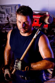 View of a garage mechanic man holding a big hammer.