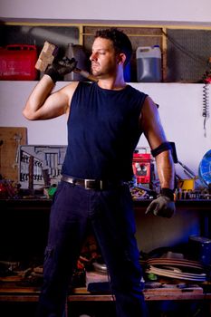 View of a garage mechanic man holding a big hammer.