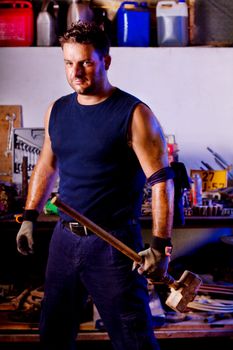 View of a garage mechanic man holding a big hammer.