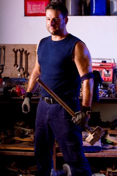 View of a garage mechanic man holding a big hammer.