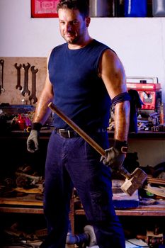 View of a garage mechanic man holding a big hammer.