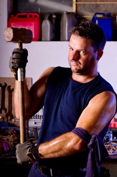 View of a garage mechanic man holding a big hammer.