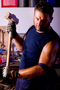 View of a garage mechanic man holding a big hammer.