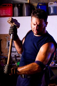 View of a garage mechanic man holding a big hammer.