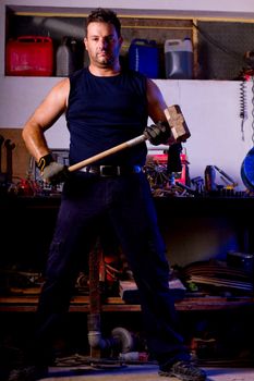 View of a garage mechanic man holding a big hammer.