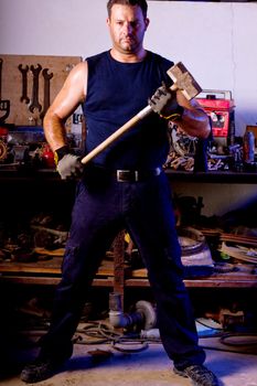 View of a garage mechanic man holding a big hammer.