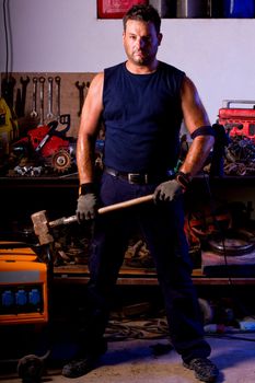 View of a garage mechanic man holding a big hammer.