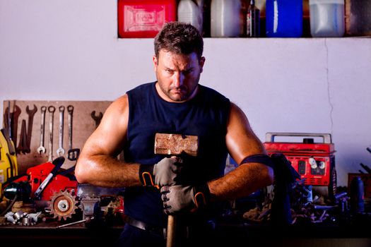 View of a garage mechanic man holding a big hammer.