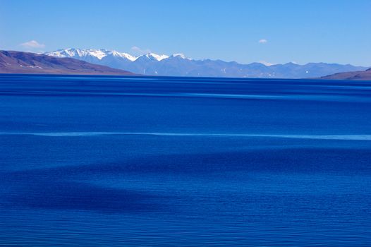 Landscape of blue lake and snow covered mountains in the highlands of Tibet