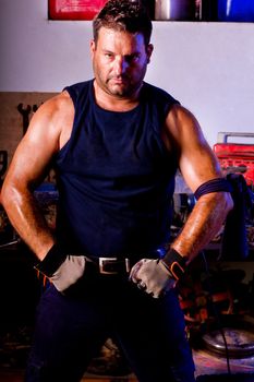 View of a garage mechanic man making a pose to show muscle.