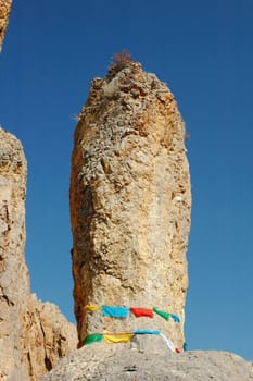 Big rock surrounded by colorful prayer flags in Tibet