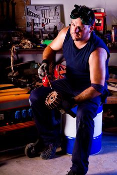 View of a garage mechanic man applying oil to a gear.