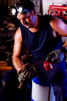 View of a garage mechanic man applying oil to a gear.