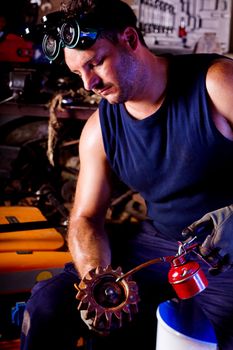 View of a garage mechanic man applying oil to a gear.