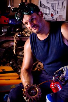 View of a garage mechanic man applying oil to a gear.