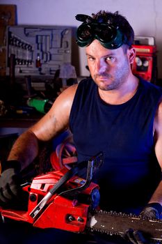 View of a garage mechanic man holding a chainsaw.