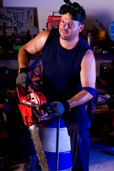 View of a garage mechanic man holding a chainsaw.