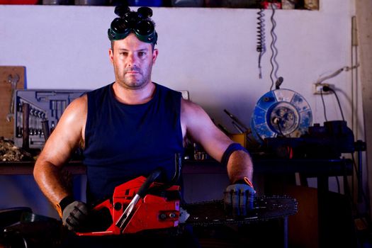 View of a garage mechanic man holding a chainsaw.