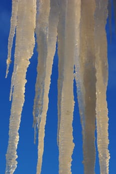 Icicles on the roof against the blue sky