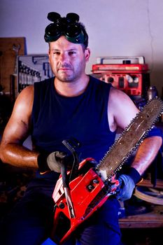 View of a garage mechanic man holding a chainsaw.