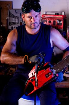 View of a garage mechanic man holding a chainsaw.