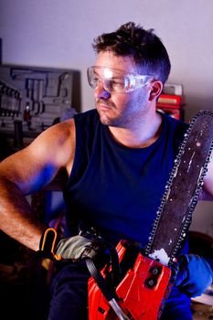 View of a garage mechanic man holding a chainsaw.