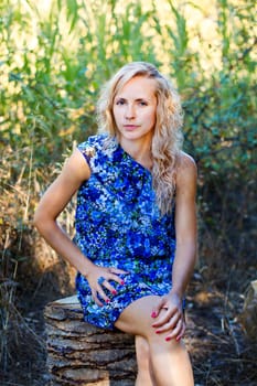 View of a beautiful young girl with a blue dress on the forest.