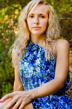 View of a beautiful young girl with a blue dress on the forest.