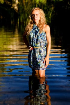 View of a beautiful young girl with a blue dress on the stream of a river.