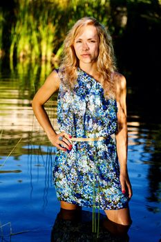 View of a beautiful young girl with a blue dress on the stream of a river.