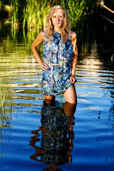 View of a beautiful young girl with a blue dress on the stream of a river.