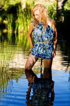 View of a beautiful young girl with a blue dress on the stream of a river.